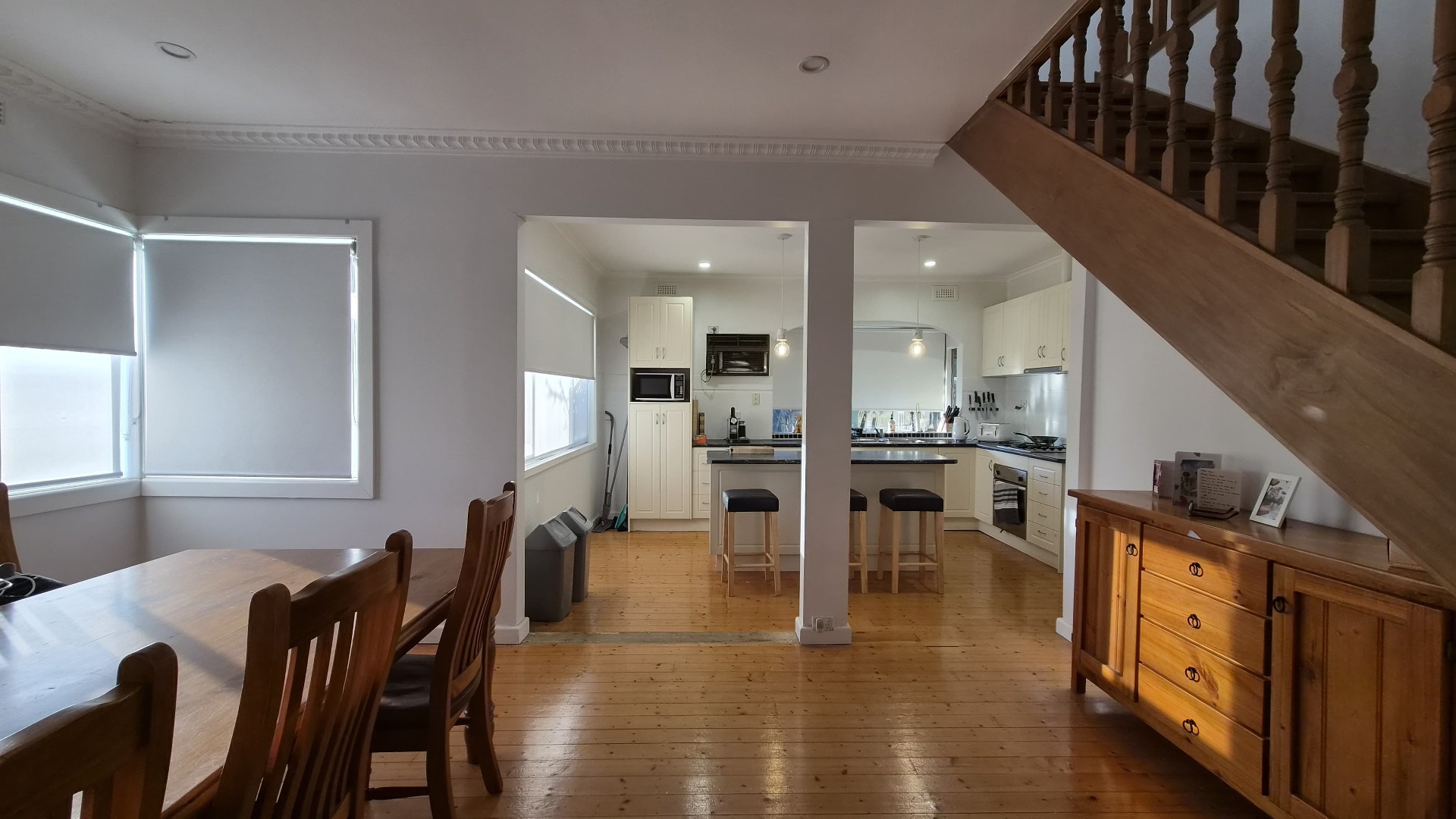 Dining and kitchen zone with timber floors and staircase